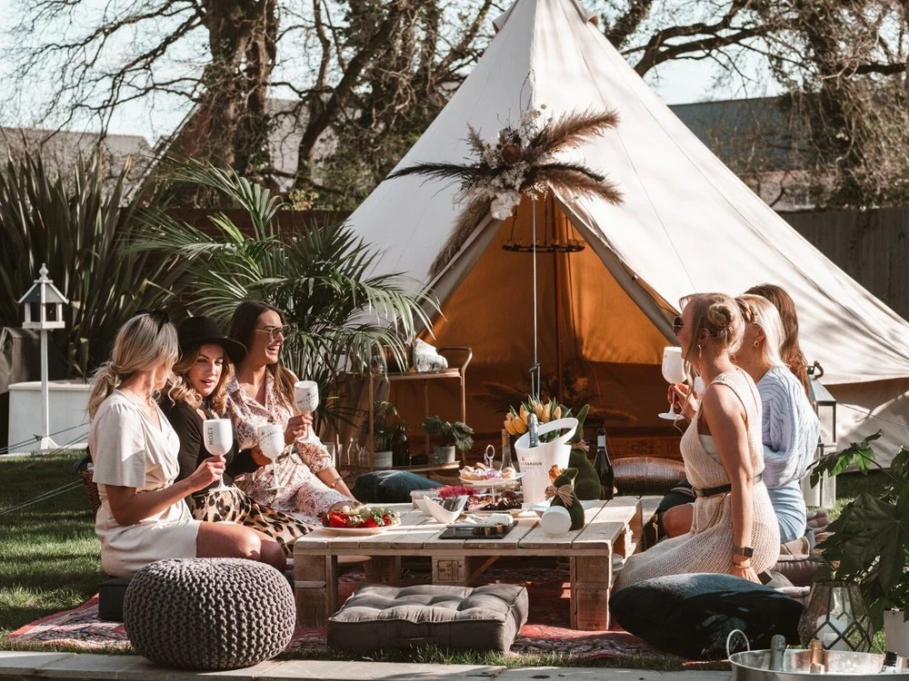Guests gathered at a low picnic table beside a decorated bell tent