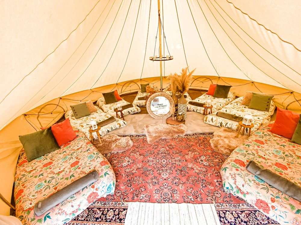 Colourful cushions and cosy mattresses arranged inside a bell tent